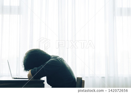 a stressed man feeling unhappy sitting with his laptop in a small room a stressed man feeling unhappy sitting with his laptop in a small room 142072656