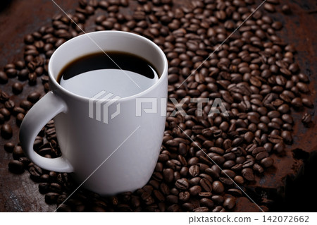 black coffee in white mug with surrounded by roasted coffee beans on dark red wood table black coffee in white mug with surrounded by roasted coffee beans on dark red wood table 142072662