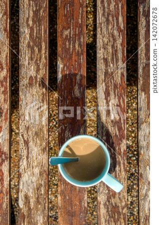 a cup of coffee on wooden bench in shade of morning sunrise with tea spoon looked like 7 o'clock's wall clock a cup of coffee on wooden bench in shade of morning sunrise with tea spoon looked like 7 o'clock's wall clock 142072678