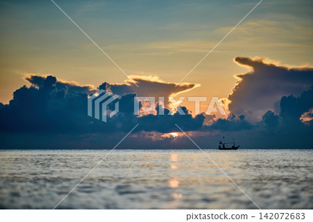 morning sunshine with the cloudy sky over the sea with small silhouette fishing boat below 142072683
