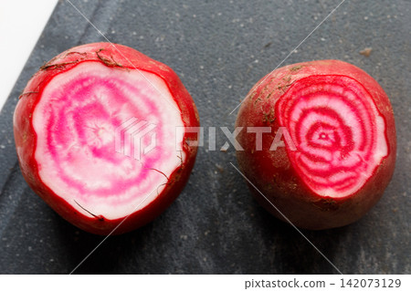 A cross-section of a fresh beet reveals a beautiful red and white swirling pattern. A cross-section of a fresh beet reveals a beautiful red and white swirling pattern. 142073129