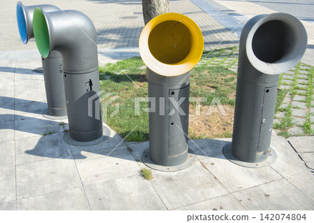 Funnel shaped colour coded waste bins along a pavement beside a lawn and tree Funnel shaped colour coded waste bins along a pavement beside a lawn and tree 142074804