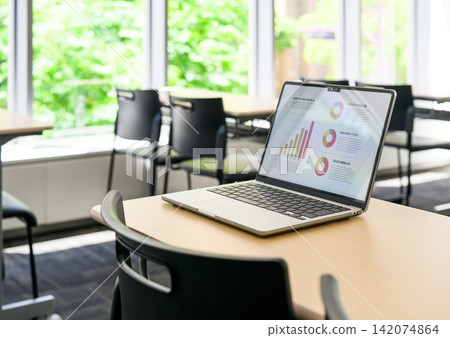 A laptop computer is open on the conference room desk. A laptop computer is open on the conference room desk. 142074864