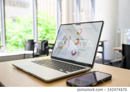 A desk with a laptop and a smartphone on it. A desk with a laptop and a smartphone on it. 142074870