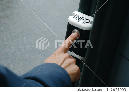 a man presses an outdoor public information button a man presses an outdoor public information button 142075003
