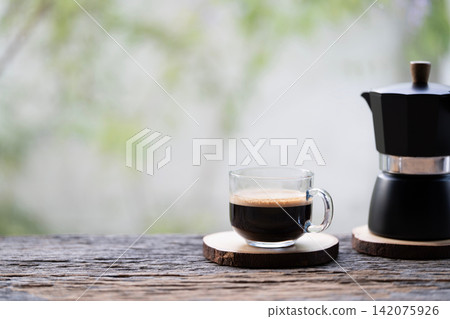 Black moka pot and coffee in a glass cup Black moka pot and coffee in a glass cup 142075926