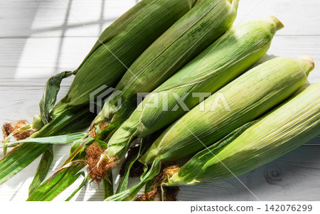 Fresh corn cobs on white wooden table Fresh corn cobs on white wooden table 142076299