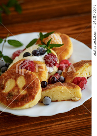 Homemade syrniki with raspberries and blueberries on wooden table Homemade syrniki with raspberries and blueberries on wooden table 142076573