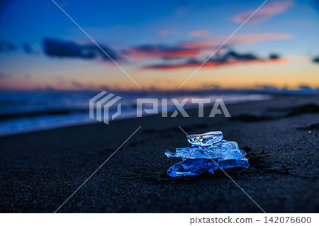 黃昏時分,靜謐的大津海岸上,如同寶石般晶瑩剔透的冰晶在暮色中閃閃發光,被沖上岸。 黃昏時分,靜謐的大津海岸上,如同寶石般晶瑩剔透的冰晶在暮色中閃閃發光,被沖上岸。 142076600