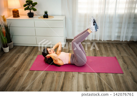 Young woman training abs on yoga mat at home Young woman training abs on yoga mat at home 142076761