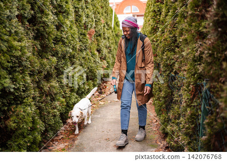Young adult woman walking a dog on a path Young adult woman walking a dog on a path 142076768