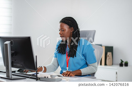 African American nurse working on computer in office African American nurse working on computer in office 142076816
