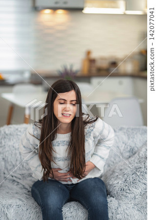 Woman suffering from severe abdominal pain and stomach ache Woman suffering from severe abdominal pain and stomach ache 142077041