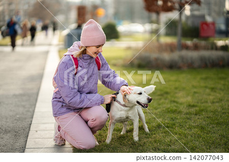 Young woman petting a labrador retriever dog in park Young woman petting a labrador retriever dog in park 142077043