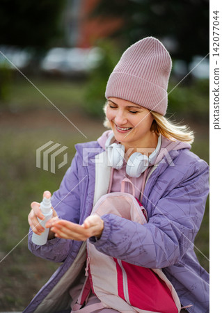 Young woman spraying hand sanitizer for hygiene outdoors Young woman spraying hand sanitizer for hygiene outdoors 142077044