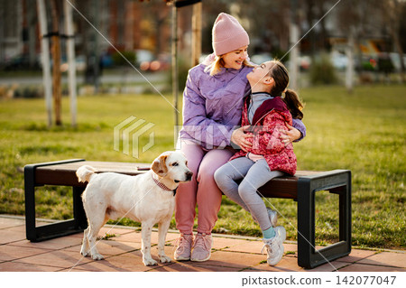 Mother and daughter bonding with pet dog in park Mother and daughter bonding with pet dog in park 142077047