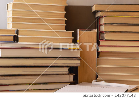 Stacks of Books and Notebook for Study, Reading and Research on a Wooden Desk 142077148