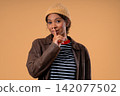 Young female teenage girl brings finger to lips with calm face, asking for quiet. Secrecy, gossip 142077502