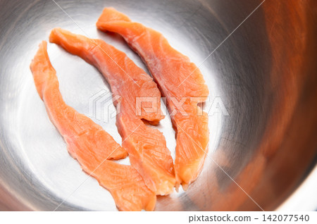 Fresh salmon fillets placed in a stainless steel bowl ready for preparation Fresh salmon fillets placed in a stainless steel bowl ready for preparation 142077540