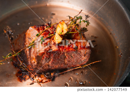 Beef roast with herbs and garlic in a stainless steel frying pan Beef roast with herbs and garlic in a stainless steel frying pan 142077549