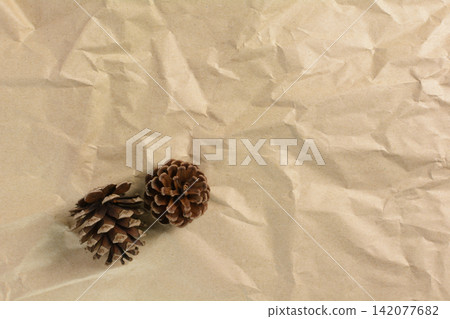 A minimalist background featuring wrinkled recycled paper and pine cones that evoke the feeling of autumn (with copy space). A minimalist background featuring wrinkled recycled paper and pine cones that evoke the feeling of autumn (with copy space). 142077682