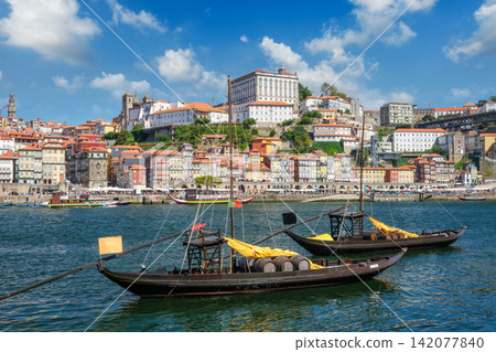 Rabelo boats on Douro River by Porto Ribeira with visible wine company names, barrels and bridge angle near Dom Luis I Bridge 142077840