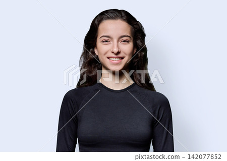 Smiling young female student looking at camera against white background Smiling young female student looking at camera against white background 142077852