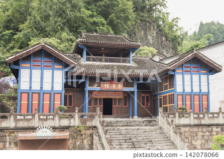 Nestled against a lush mountain cliff, this traditional wooden pavilion showcases vibrant Miao architectural heritage within the historic Chiyou Jiuli City complex. Nestled against a lush mountain cliff, this traditional wooden pavilion showcases vibrant Miao architectural heritage within the historic Chiyou Jiuli City complex. 142078066
