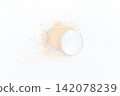 Open compact reveals soft natural toned powder. Slight dusting suggests gentle application. Minimalist white background enhances product clarity. Ideal for beauty, skincare, or makeup editorial use 142078239