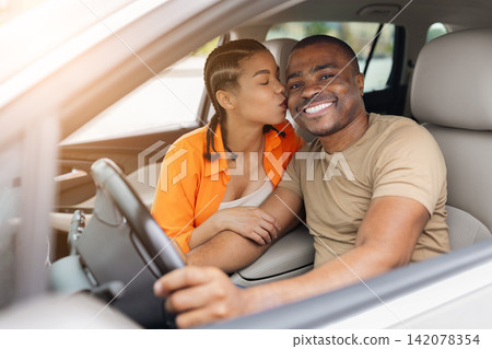 Affectionate young African American couple sitting in car, woman kissing mans cheek Affectionate young African American couple sitting in car, woman kissing mans cheek 142078354