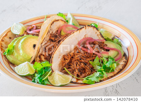 Pulled beef tacos with avocado pickled onions cilantro lime Mexican street food Pulled beef tacos with avocado pickled onions cilantro lime Mexican street food 142078410