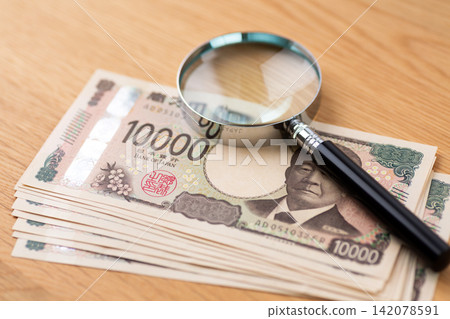 10萬日圓面額的1萬日元鈔票和一個放大鏡 10萬日圓面額的1萬日元鈔票和一個放大鏡 142078591
