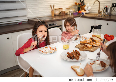 Children eating breakfast in kitchen, enjoying family meal time Children eating breakfast in kitchen, enjoying family meal time 142078726