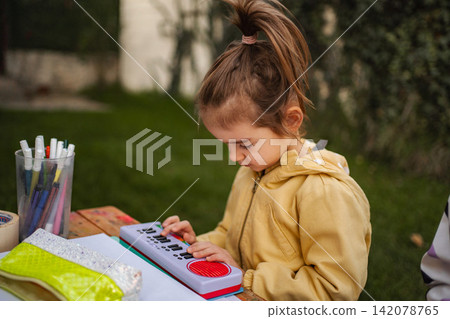 Little girl playing toy keyboard outdoors exploring creativity Little girl playing toy keyboard outdoors exploring creativity 142078765