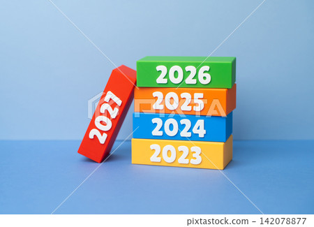 A stack of dominoes with the years 2027. Preparing for the New Year, making plans and setting goals. Strategic vision, goal setting, new beginnings, economic forecasts A stack of dominoes with the years 2027. Preparing for the New Year, making plans and setting goals. Strategic vision, goal setting, new beginnings, economic forecasts 142078877