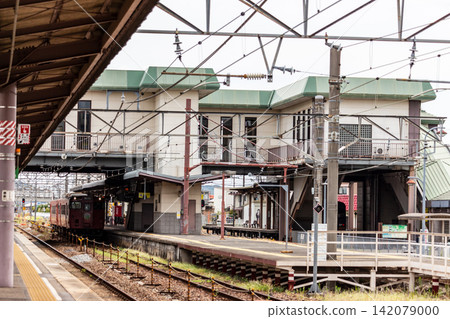 A scene of a train station platform and overpass in a regional city (daytime, outdoors). A scene of a train station platform and overpass in a regional city (daytime, outdoors). 142079000