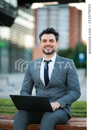 Happy businessman working on laptop outdoors Happy businessman working on laptop outdoors 142079054