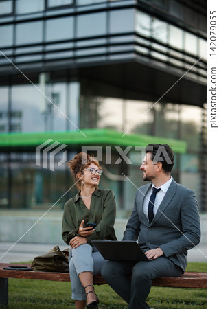 Business colleagues collaborating outdoors on laptop and smartphone Business colleagues collaborating outdoors on laptop and smartphone 142079055