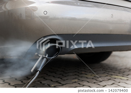 Car exhaust pipe emits dense smoke during emission test on city pavement. Pollution control device measures harmful gases. Service car center garage workshop. Automobile repair check up diagnosis Car exhaust pipe emits dense smoke during emission test on city pavement. Pollution control device measures harmful gases. Service car center garage workshop. Automobile repair check up diagnosis 142079400