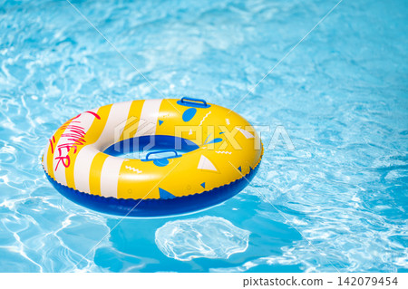 Yellow inflatable ring floating in a clear blue swimming pool, creating a bright summer leisure scene. Yellow inflatable ring floating in a clear blue swimming pool, creating a bright summer leisure scene. 142079454