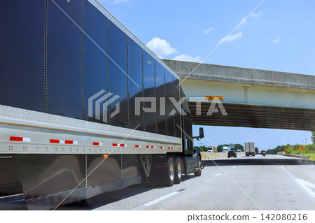 Truck drives on highway beneath bridge with height limit sign. Truck drives on highway beneath bridge with height limit sign. 142080216