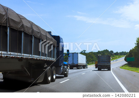 Several large trucks travel on US interstate highway in American rural area. Several large trucks travel on US interstate highway in American rural area. 142080221