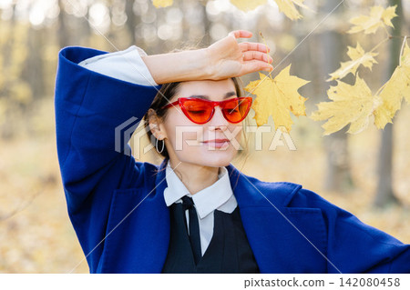 Beautiful young woman enjoying autumn day in nature, walking down the forest path covered with colorful fallen leaves and relaxing Beautiful young woman enjoying autumn day in nature, walking down the forest path covered with colorful fallen leaves and relaxing 142080458