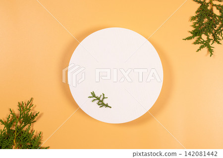 White round podium with cedar branches on orange background White round podium with cedar branches on orange background 142081442