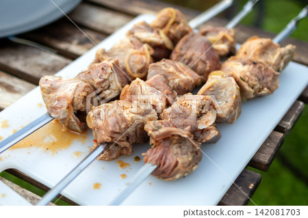 Marinated Meat Skewers Ready for Grilling on Garden Picnic Table Marinated Meat Skewers Ready for Grilling on Garden Picnic Table 142081703