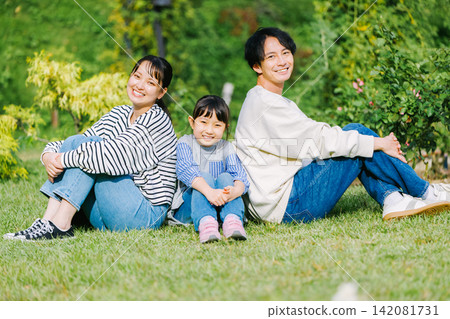 Close family sitting on the grass in the park Close family sitting on the grass in the park 142081731