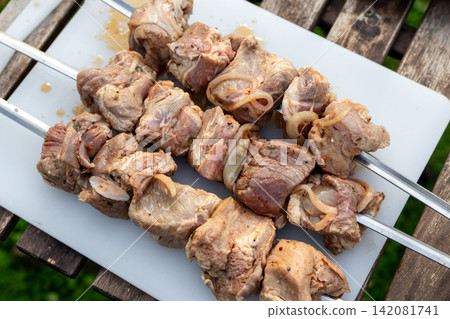 Marinated Meat Skewers Ready for Grilling on Garden Picnic Table Marinated Meat Skewers Ready for Grilling on Garden Picnic Table 142081741