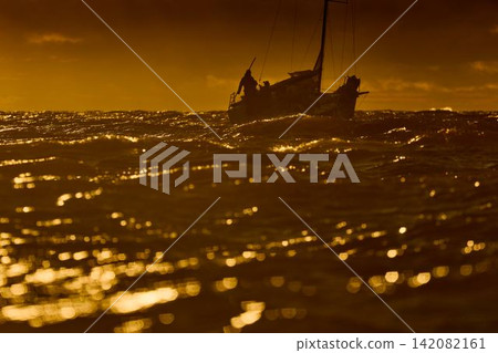 Yachtsmen are sitting amicably on board the boat, sailing boat is in sailing regatta in the Gulf of Finland at sunset, magic splashing water, teamwork Yachtsmen are sitting amicably on board the boat, sailing boat is in sailing regatta in the Gulf of Finland at sunset, magic splashing water, teamwork 142082161