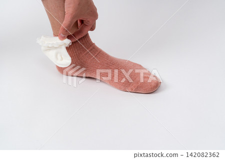 A foot wearing a pink sock and a small white sock A foot wearing a pink sock and a small white sock 142082362