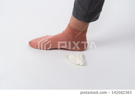 一隻腳和一隻小襪子站在白色背景上。 一隻腳和一隻小襪子站在白色背景上。 142082365